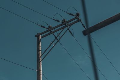 Low angle view of electricity pylon against blue sky