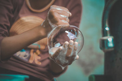 Midsection of child playing with soap bubble