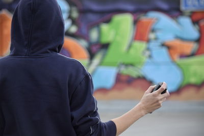 Rear view of a man holding spray paint