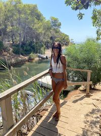 Portrait of young woman standing by railing against trees. màgic island