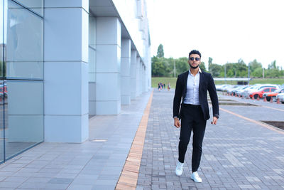 Young businessman standing against building