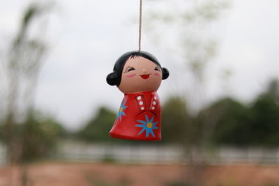 Close-up of figurine hanging against sky