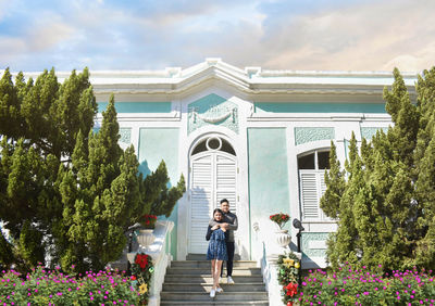 Portrait of couple standing on staircase against building