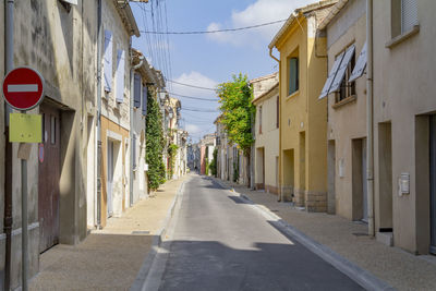 Empty road amidst buildings in city