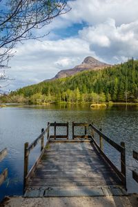 Pier on lake against cloudy sky