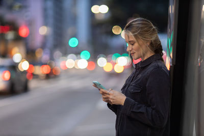 Woman with smartphone at night time on the street. mobile phone, technology, urban