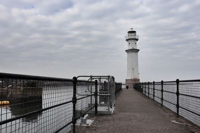 Lighthouse by sea against sky