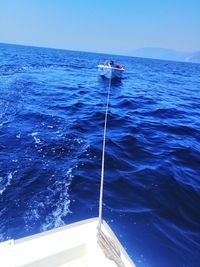 Boat sailing in sea against clear blue sky