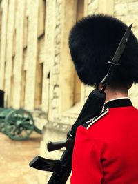 Rear view of man in uniform holding rifle while standing outdoors