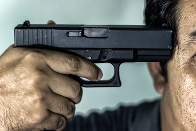 Midsection of man shooting himself with handgun