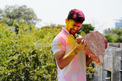 Young man with powder paint while holding rock during holi