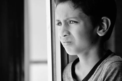 Boy looking through window at home