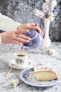 Still life with black tea and cheese cake, spring bouquet of delicate lilac flowers.