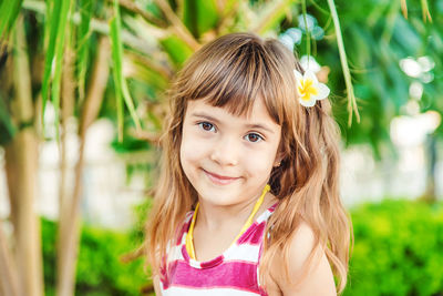 Portrait of young woman standing against plants