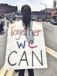 Rear view of man with text on street in city