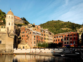 Buildings by river against sky in city