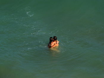 High angle view of romantic couple embracing in sea