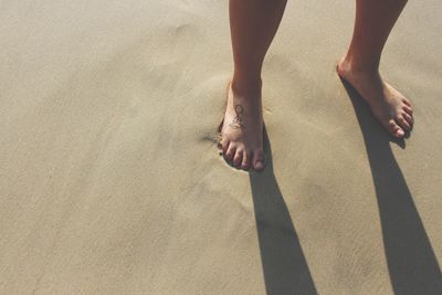 Low section of woman standing on sand at beach