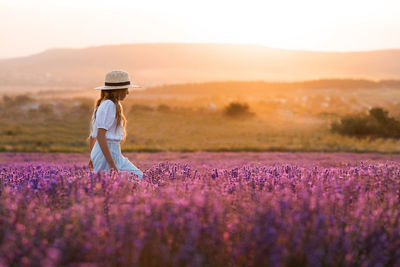 Stylish teenage girl 8-9 year old walking in blooming lavender flower field over nature sunny