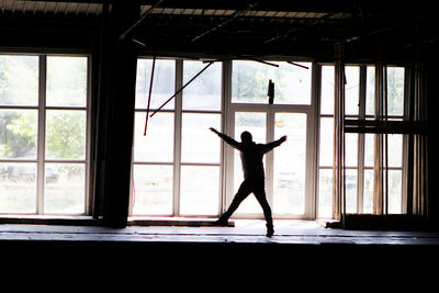 Man with arms outstretched standing by window