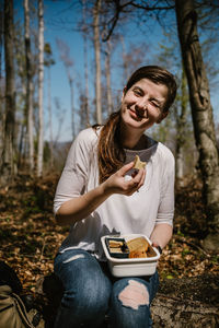Portrait of woman winking while having food at forest