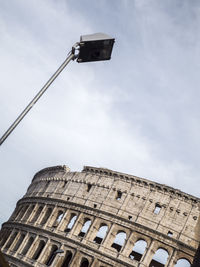 Low angle view of coliseum against cloudy sky