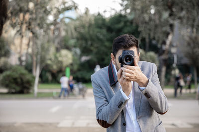 Man photographing through camera against trees