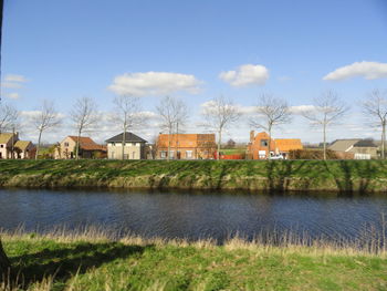 Houses by river against sky