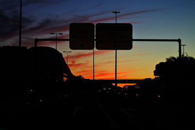 Road sign on street against sky at dusk