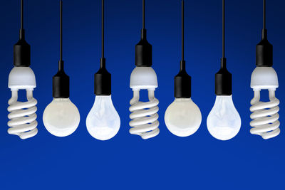 Close-up of illuminated light bulb hanging against black background