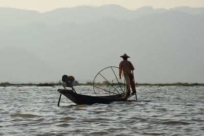 Men on boat in sea against sky