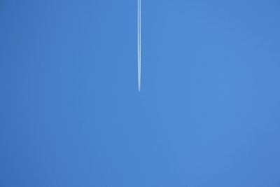 Low angle view of vapor trail against clear blue sky