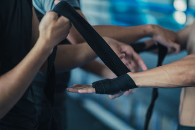 Friend tying bandage on players hand at gym