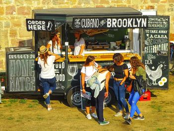Happy female friends standing by food truck on field