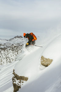 Side view of hiker with backpack skiing on snowcapped mountain