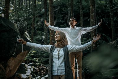 Full length of friends standing by tree in forest