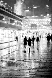 People walking on illuminated street at night