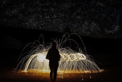 Rear view of woman standing by illuminated wire wool at night