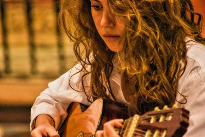 Young woman playing guitar in concert