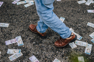 Low section of person walking by paper currency on street