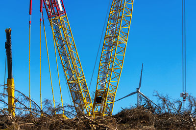 Low angle view of crane against clear blue sky