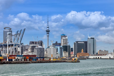 Sea by modern buildings against sky in city