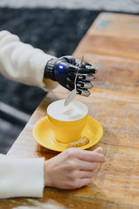 Cropped hand of woman holding drink on table