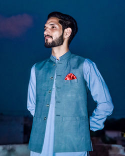 Portrait of man standing against blue background