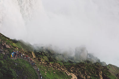 High angle view of people standing on mountain during foggy weather