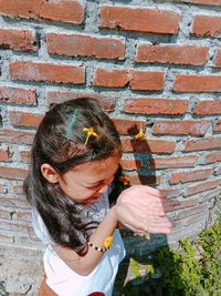 Woman holding umbrella against brick wall