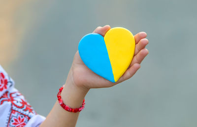 Cropped hand holding heart shape against sky