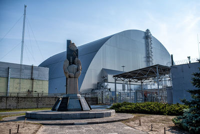 Statue by building against sky