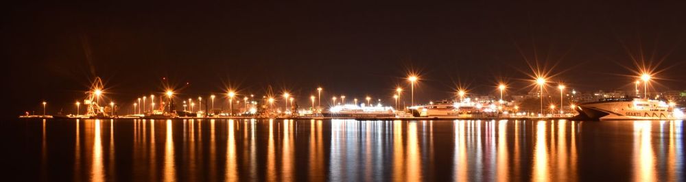 Illuminated boats moored at harbor against sky at night