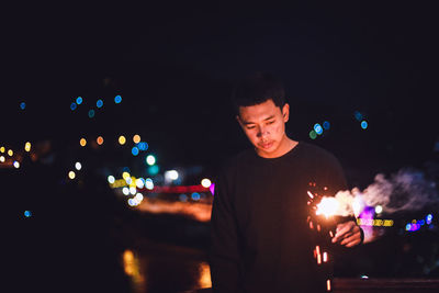 Man holding sparkler at night